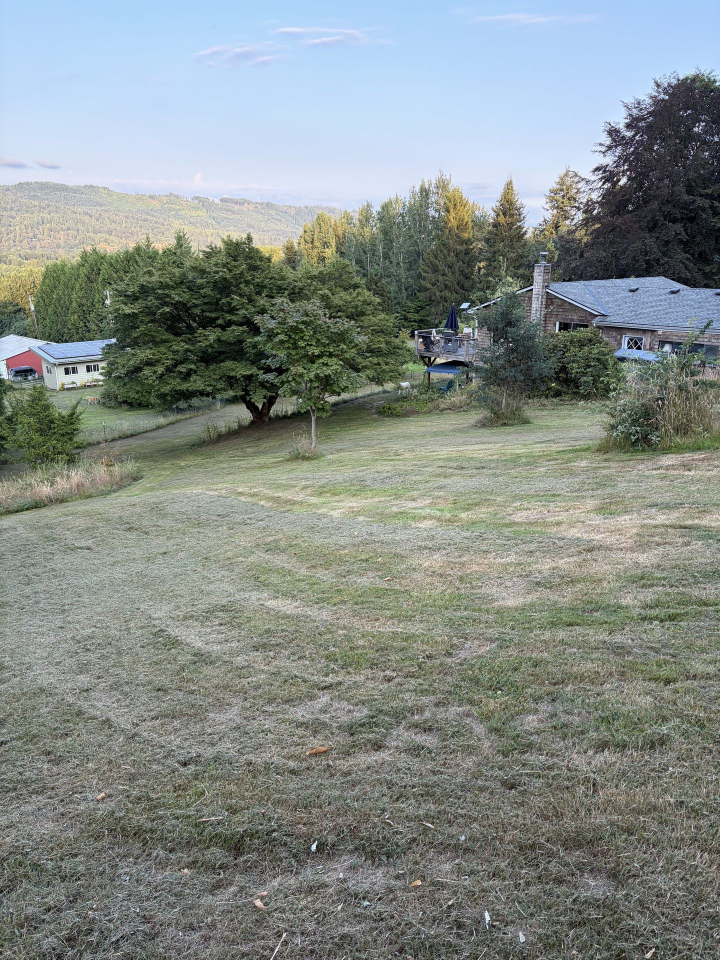 Wide view of the property lawn, home, and mountain backdrop